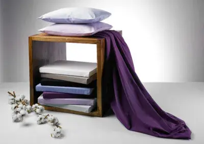 Holzhocker mit Kissenstapel und violettem Stoff, Bettwäsche-Set im Studio