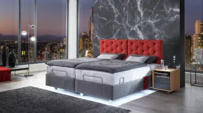 Modernes Boxspringbett mit rotem Kopfteil im Schlafzimmer mit Stadtblick