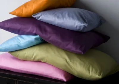 Stapel bunter Kissen in Pastellfarben auf dunkler Oberfläche, Wohndeko