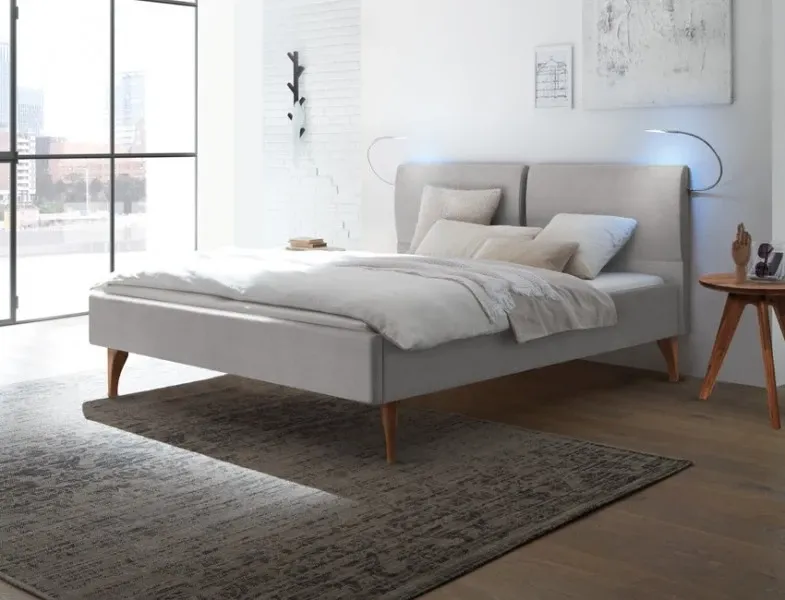 Modernes Polsterbett in hellem Schlafzimmer mit Teppich und großem Fenster